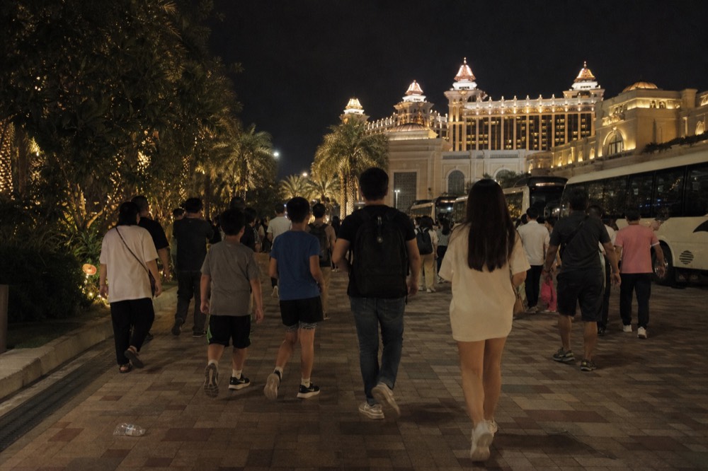 Crowded promenade outside a Cotai resort entrance at night