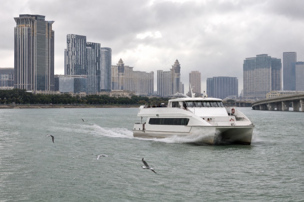 A high-speed catamaran ferry cutting across open water toward Macau