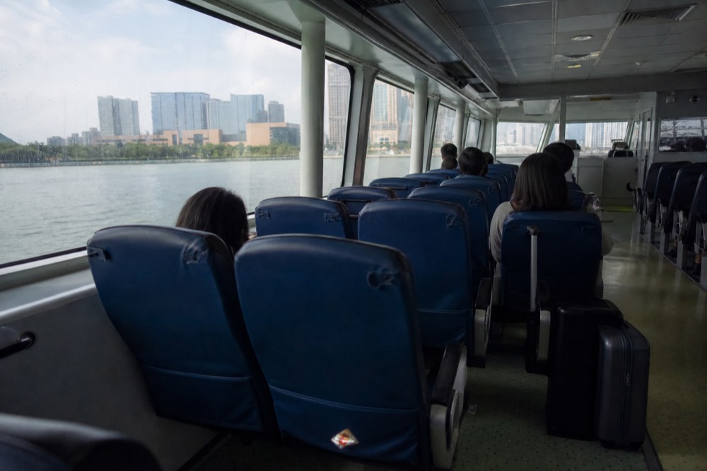 Passengers seated inside a bright high-speed ferry cabin during a Hong Kong to Macau crossing
