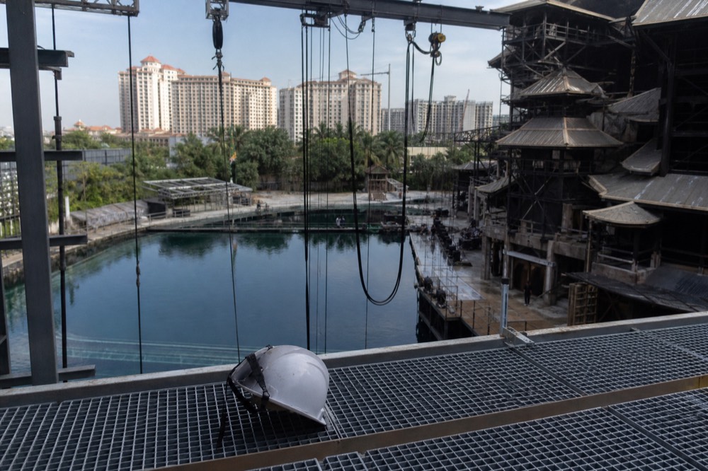 Backstage view of theatrical rigging and a large prop above an empty pool