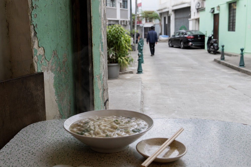 Steam rising from a bowl of noodles on a small restaurant table
