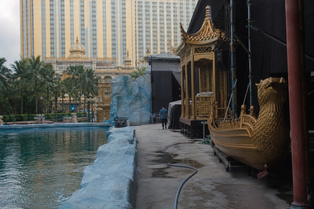 Golden props and stage scenery beside a large performance pool backstage