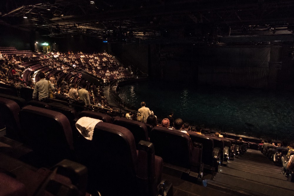 Theatre seating tiers rising around a stage pool