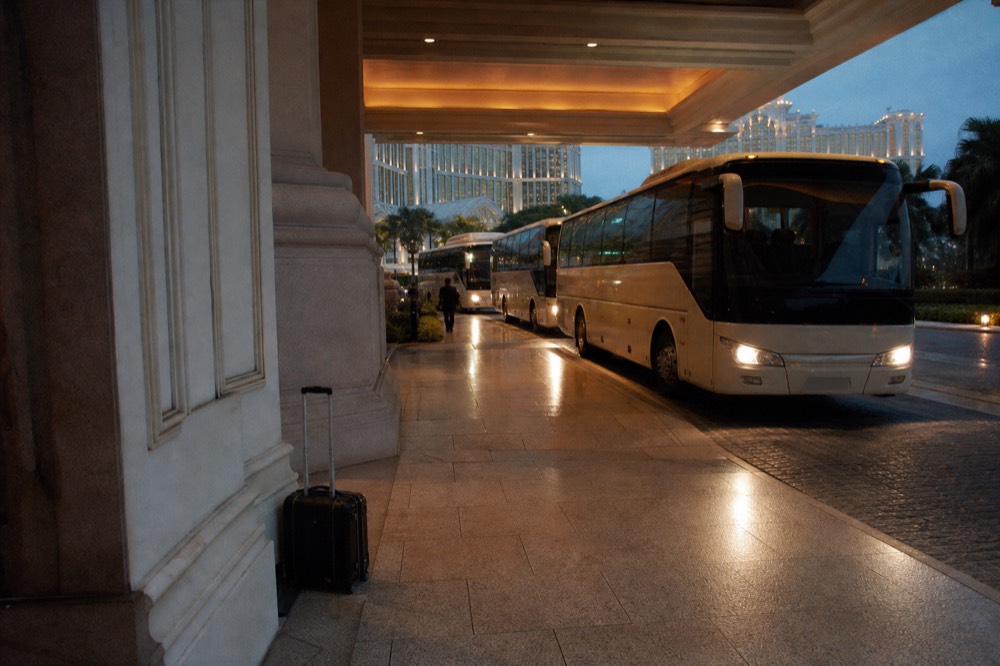 Resort shuttle buses lined up at a Cotai porte-cochere in the evening