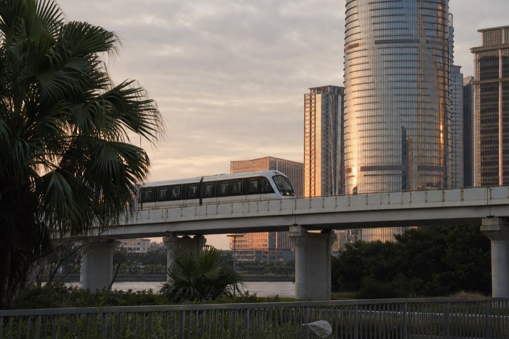 Elevated driverless LRT train on a viaduct above Cotai at dusk