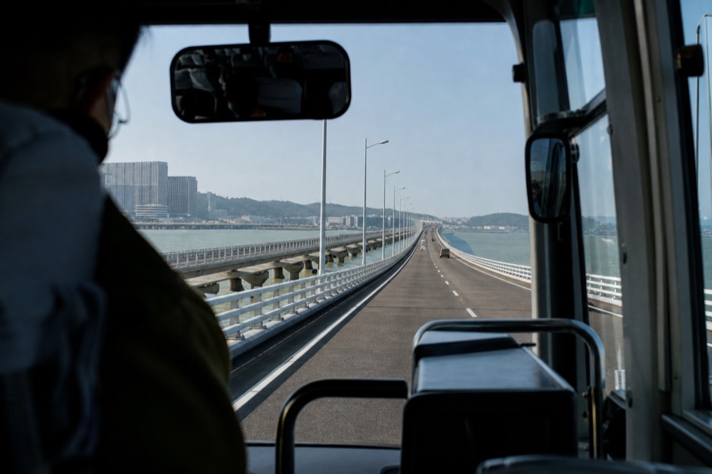 A shuttle bus on a long cross-sea bridge under a wide sky