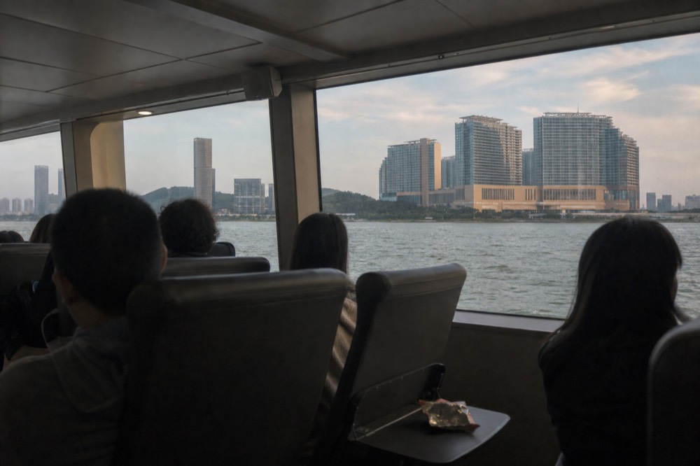 A ferry cabin interior with passengers seated for a daytime crossing