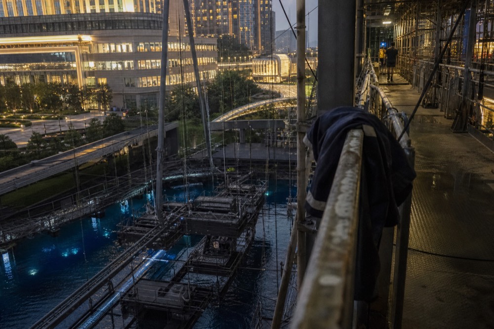 Backstage walkway above a theatre stage pool with rigging and prop structures below