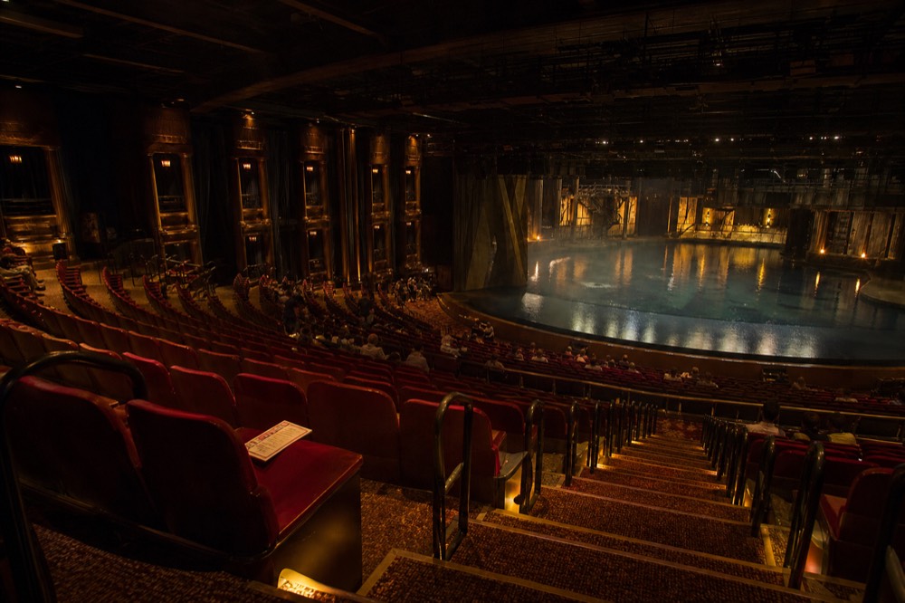 Audience seating rising around the circular pool stage of the Dancing Water Theater