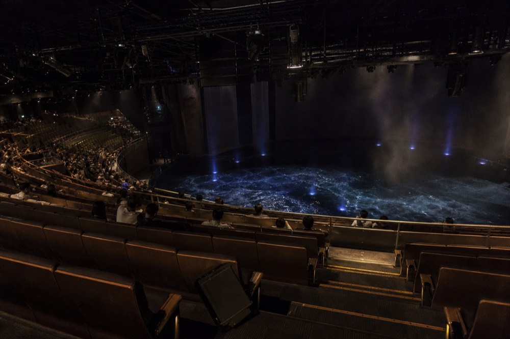 Curved rows of theatre seating facing a dark pool stage lit from below