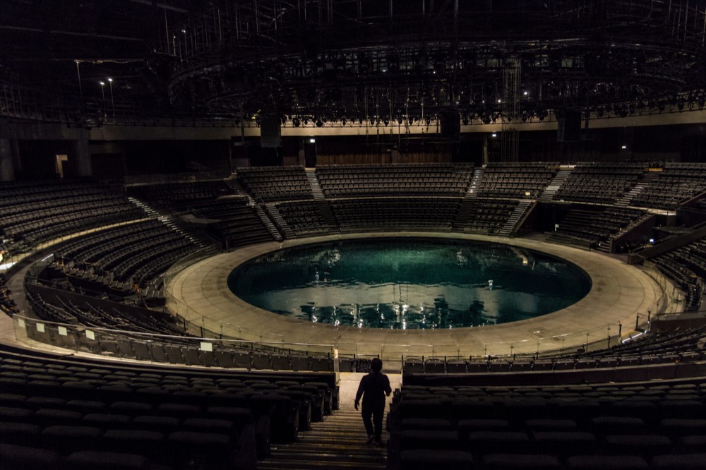 An aerial view of a circular pool stage surrounded by rising curved seating rows