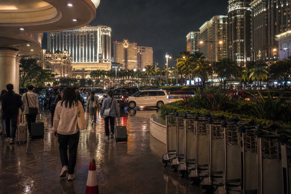The illuminated exterior of a Cotai resort at night with arrivals heading inside