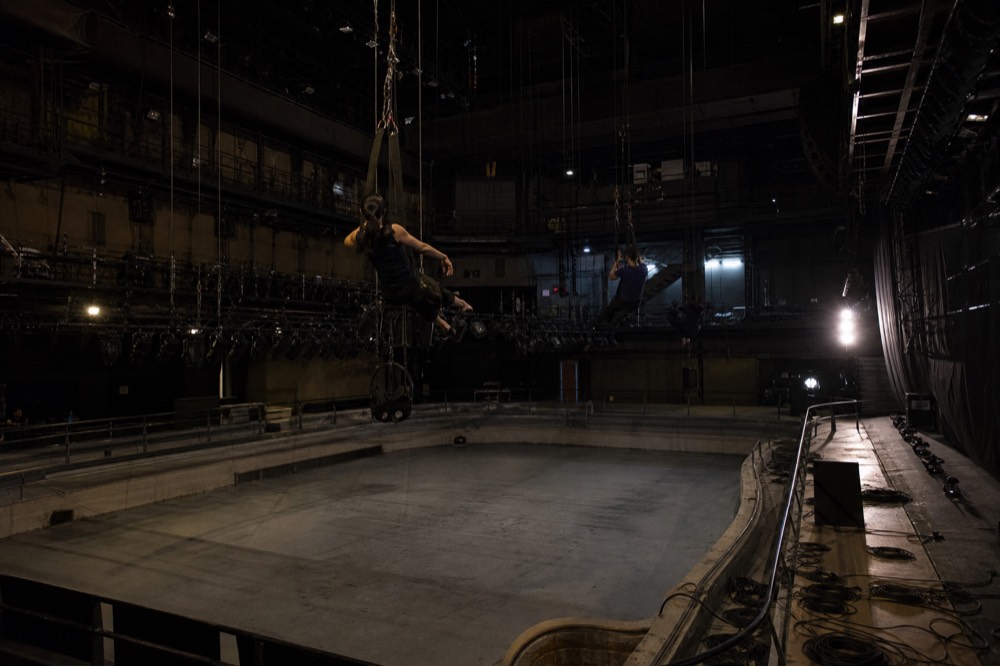 Aerialists rehearsing on rigs above an empty stage