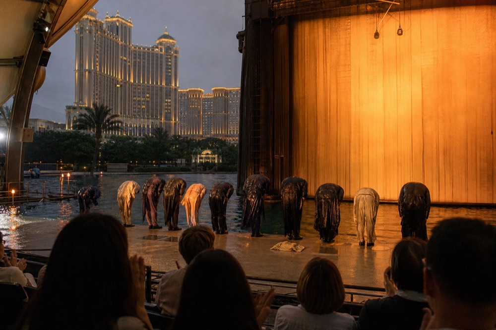 Performers taking a bow in front of a lit theatre curtain