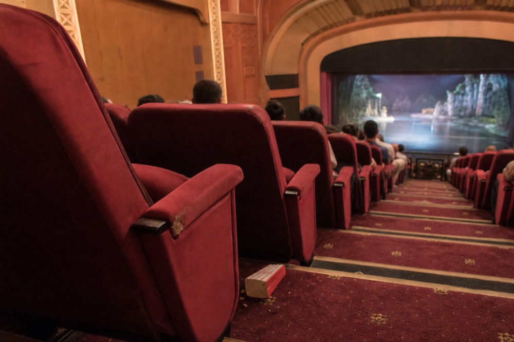 Rows of theatre seats facing a lit proscenium stage