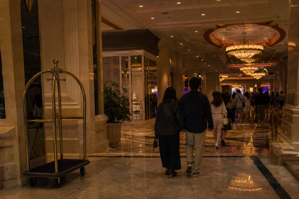 An evening crowd walking through a bright resort interior toward a theatre lobby