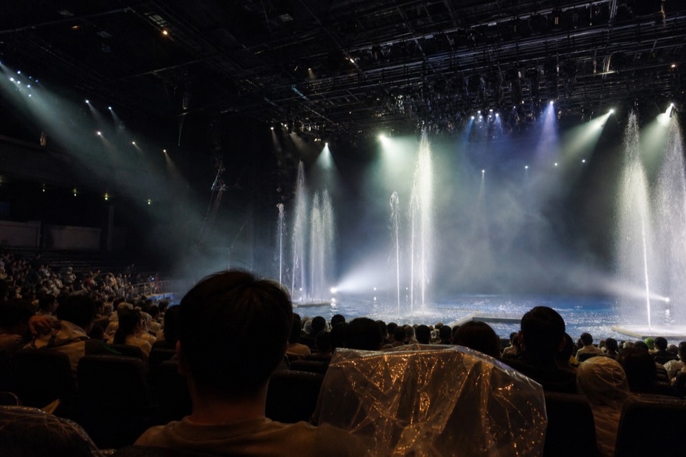 Water fountains erupting on a theatre stage under bright spotlights
