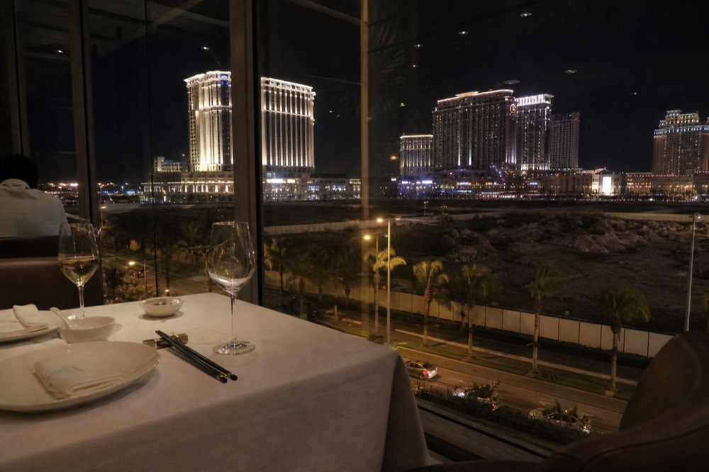 Elegant hotel restaurant table set for dinner with resort lights beyond